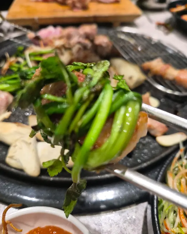 잘 구워진 고기를 쌈 채소와 함께 먹는 모습