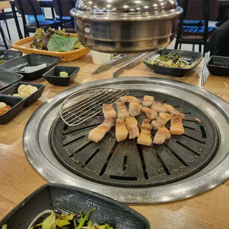 테이블 위에서 맛있게 구워지고 있는 돼지고기의 모습