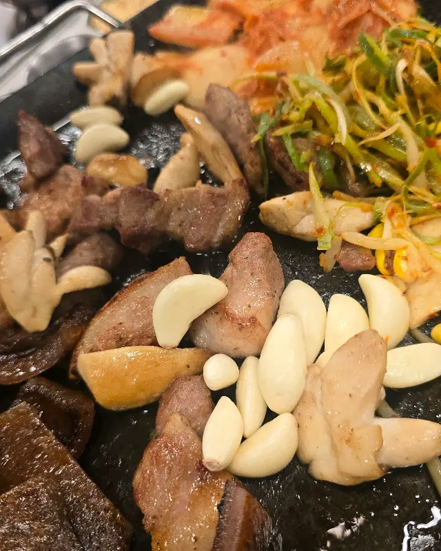 불판 위에서 익어가는 뒷고기, 김치, 마늘