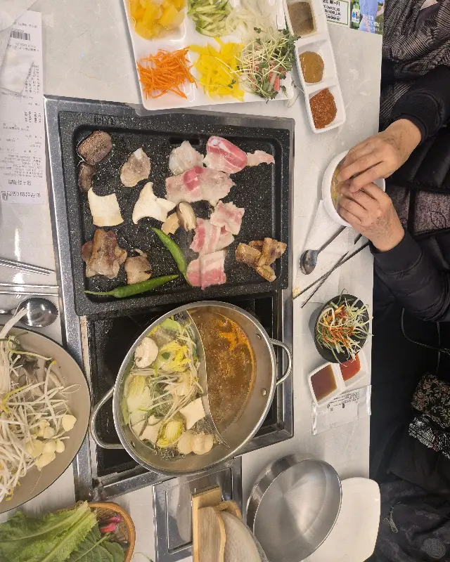 불판 위에서 지글지글 익어가는 삼겹살과 샤브샤브 냄비