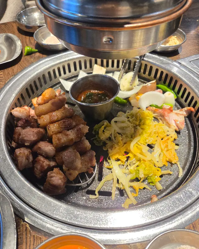 잘 구워진 갈매기살과 곁들임 채소들이 불판 위에 놓여있는 모습