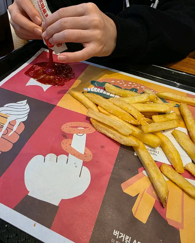 케첩을 짜서 감자튀김을 찍어 먹는 모습