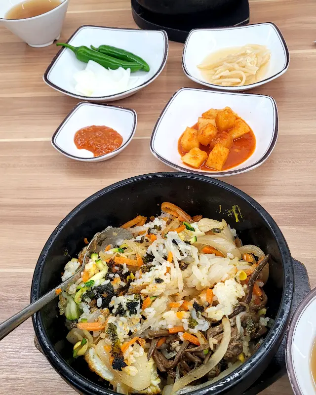 돌솥비빔밥과 다양한 밑반찬이 놓인 테이블