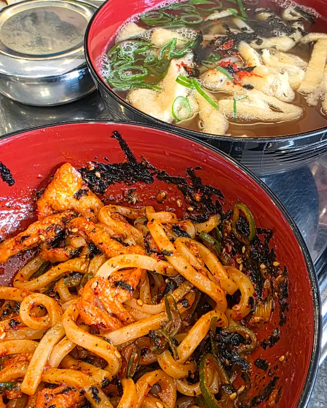 빨간 양념의 비빔 우동과 맑은 국물의 우동이 나란히 놓여있다.