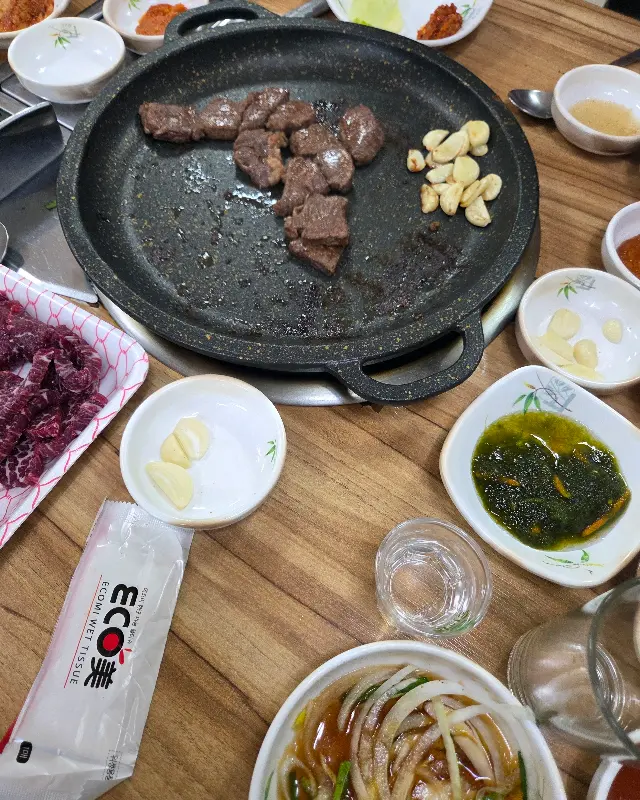 불판 위에서 익어가는 한우와 곁들여 먹는 다양한 밑반찬들이 풍성한 식탁을 연출한다.