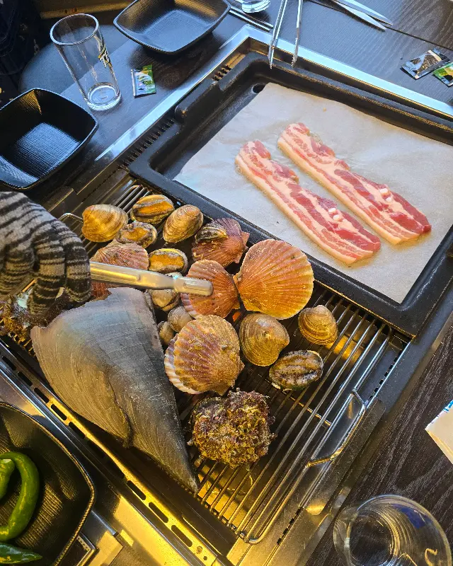 불판 위에 올려진 조개와 삼겹살