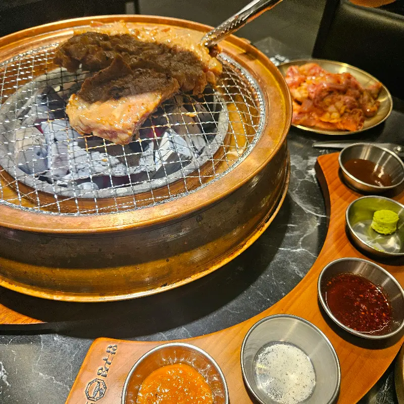 숯불 화로 위 석쇠에 돼지갈비가 맛있게 구워지고 있는 모습