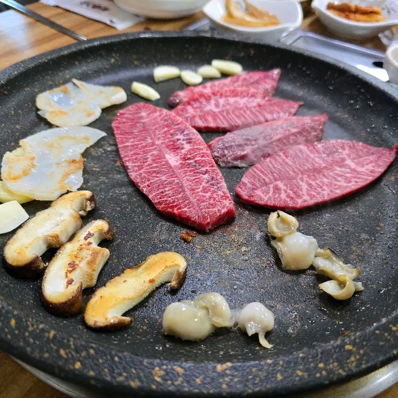 잘 구워진 한우, 키조개, 표고버섯이 불판 위에서 조화로운 색감을 뽐내고 있다.