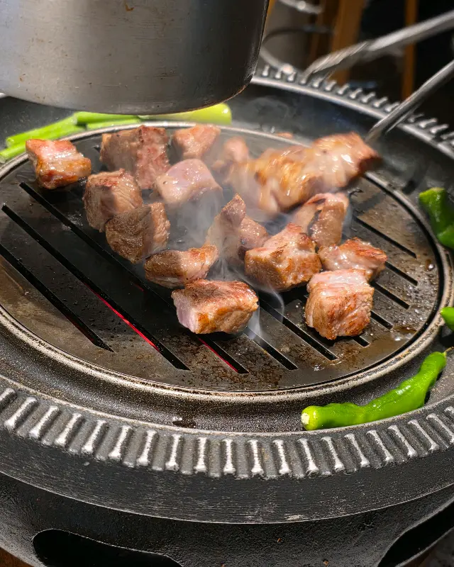 불판 위에서 구워지고 있는 돼지고기의 클로즈업 샷