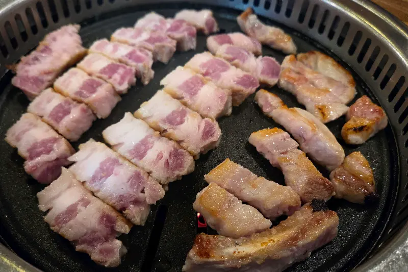 불판 위에 가지런히 놓인 삼겹살