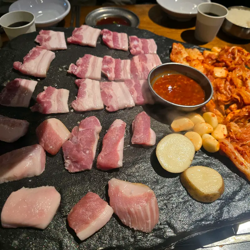 돌판 위에 익어가는 삼겹살, 김치, 마늘