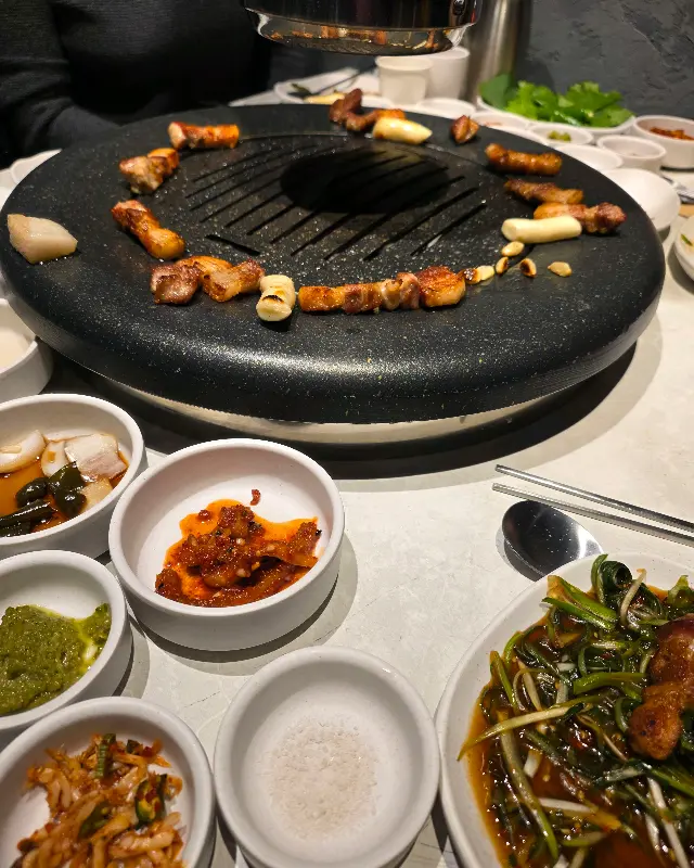 맛있게 익은 고기와 반찬, 쌈 채소가 놓인 테이블 전경