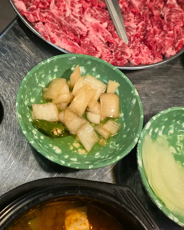 테이블 위에 놓인 밑반찬과 갈비살