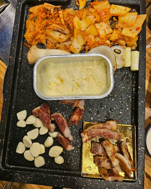 불판 가득한 삼겹살과 김치, 구운 마늘