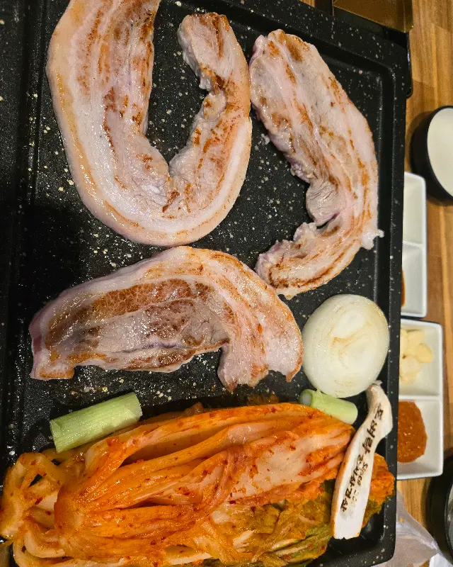 불판 위의 삼겹살과 김치