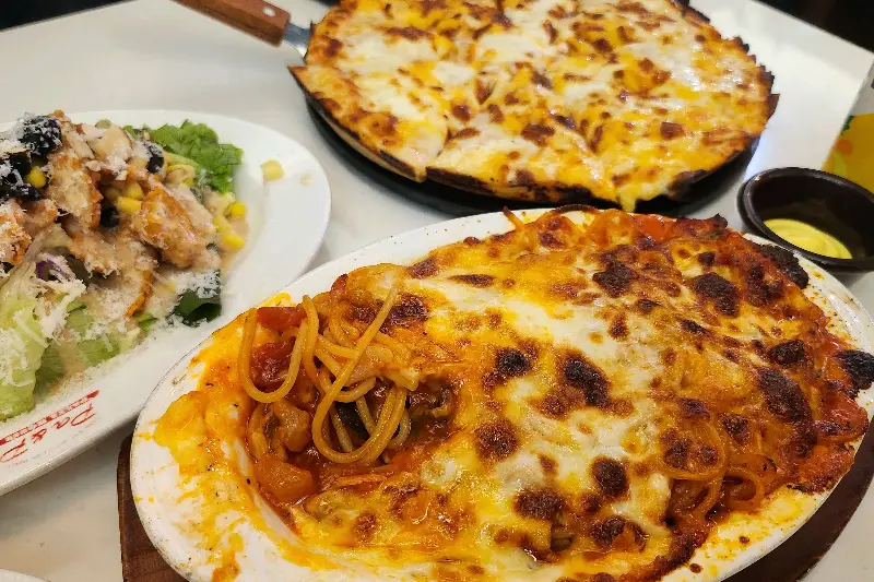 테이블 위에 놓인 피자, 파스타, 샐러드