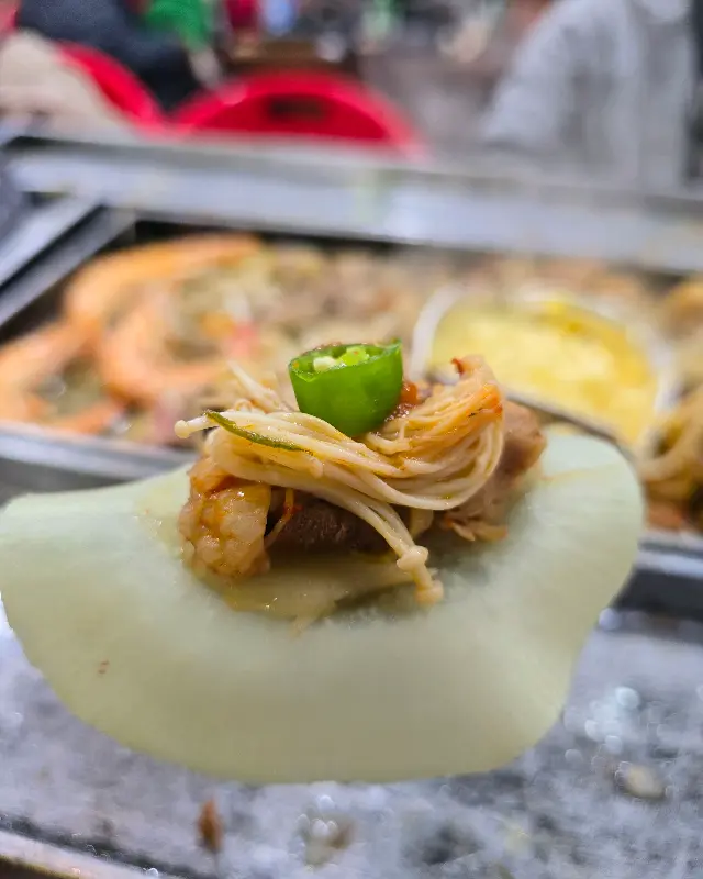 해물과 야채, 고기를 함께 싸 먹는 모습