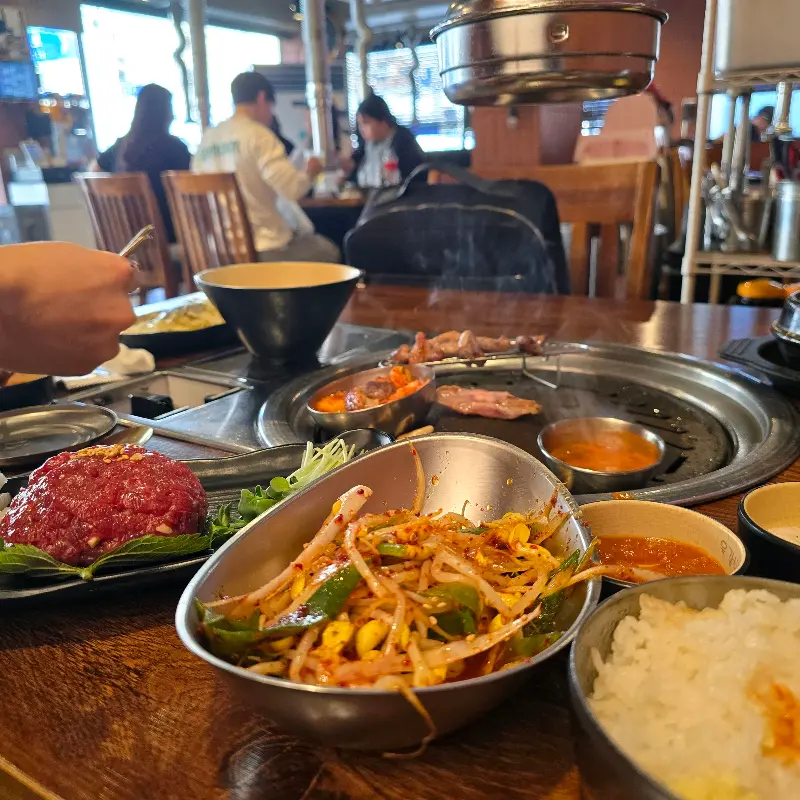 테이블 가득 차려진 밑반찬과 고기