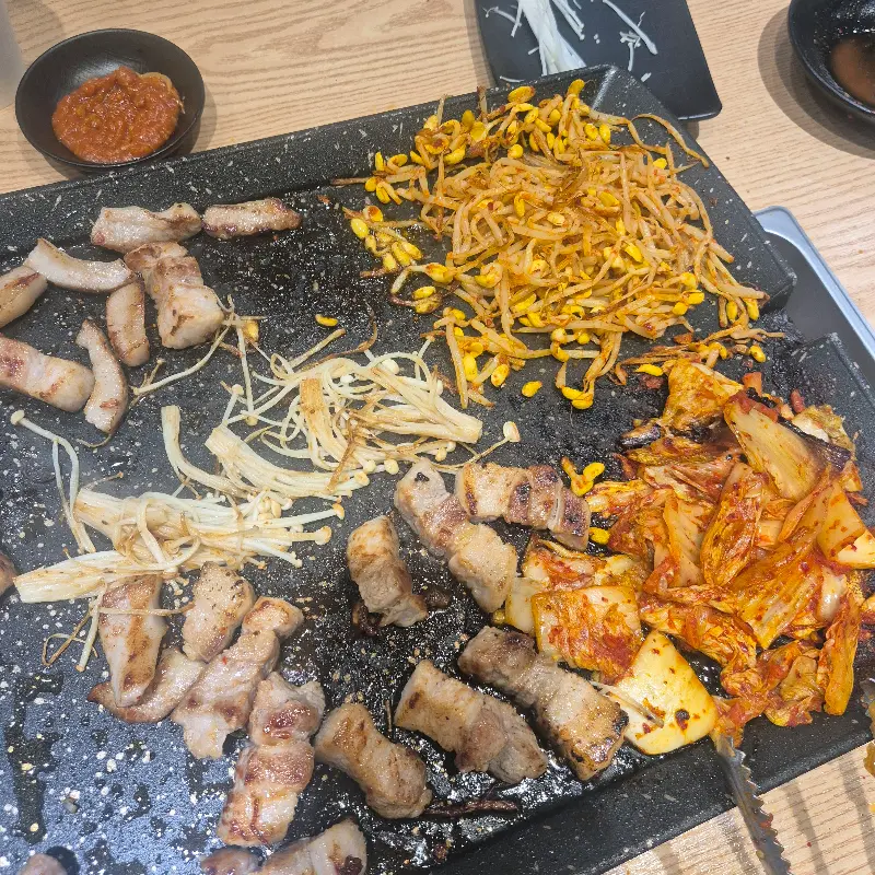 불판 위에서 노릇하게 구워지는 삼겹살과 김치