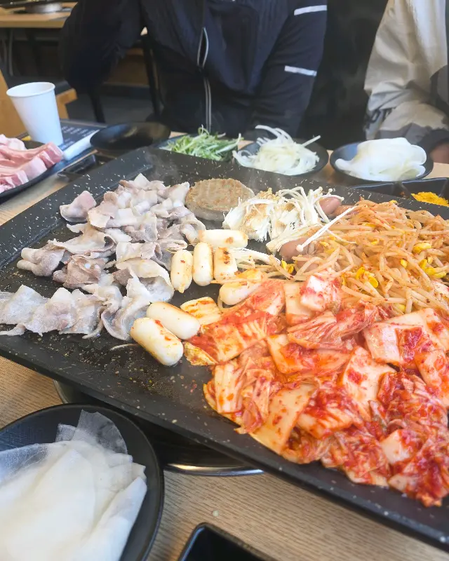 불판 위에서 익어가는 우삼겹과 김치의 환상적인 조합