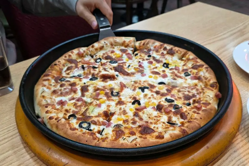 피자가 검정색 팬에 담겨 있다.