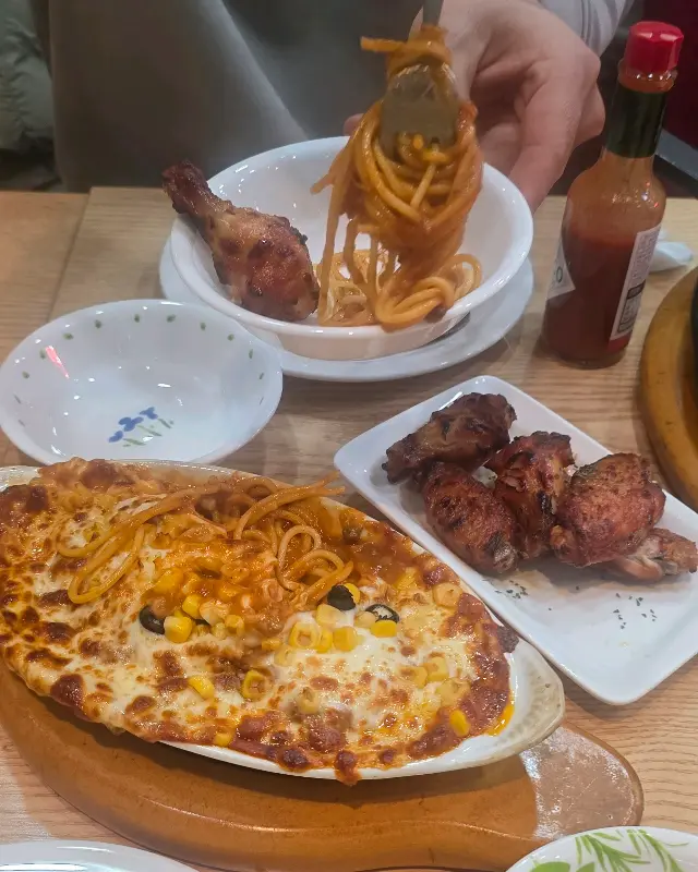 스파게티, 핫윙, 닭다리가 테이블 위에 놓여 있다.