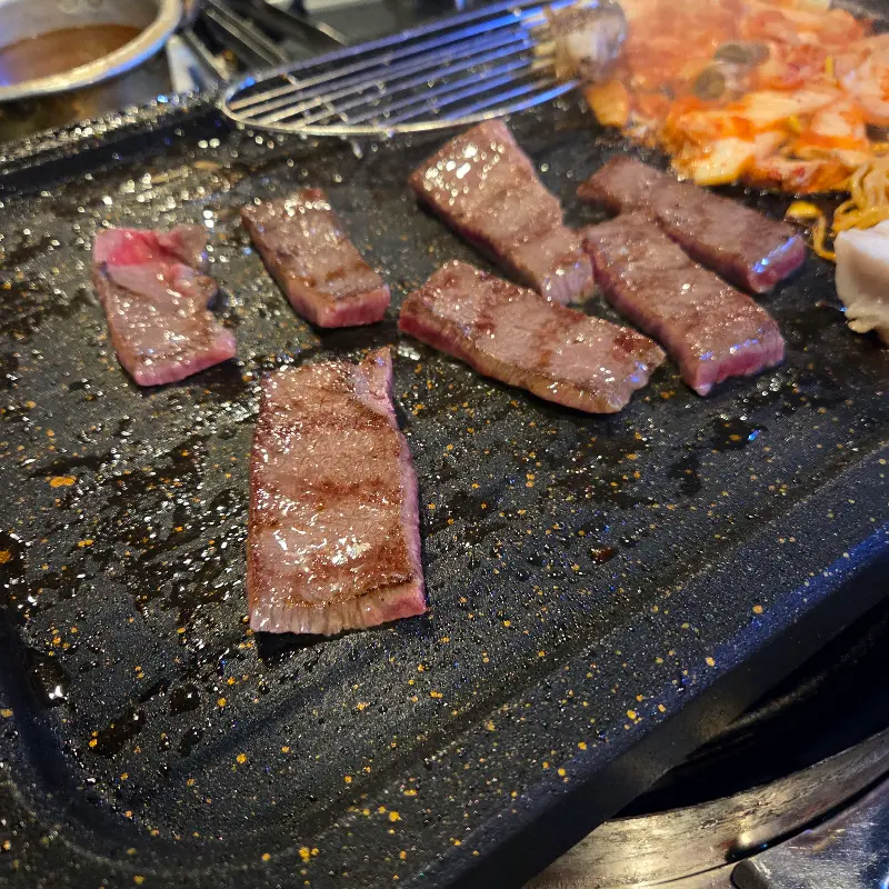 잘 익은 소고기 한 점을 젓가락으로 들어올린 모습