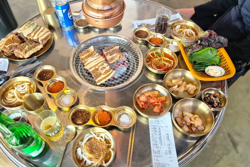 테이블 가득 차려진 생갈비와 곁들임 찬들