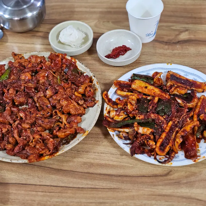 오징어 불고기와 닭 불고기가 테이블 위에 나란히 놓여 있는 모습