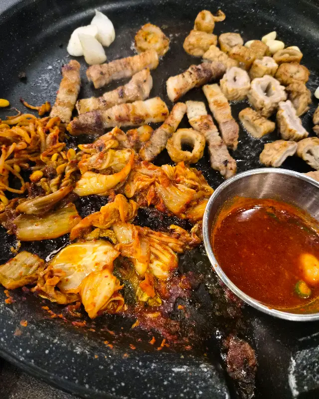 불판 위에 함께 구워지고 있는 막창, 삼겹살, 김치, 콩나물
