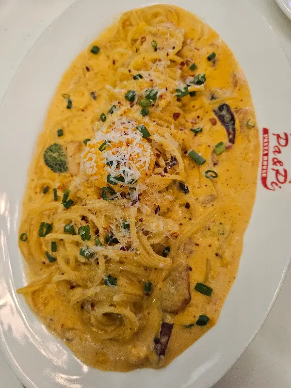 접시에 담긴 크림 파스타 위로 파슬리가 뿌려져 있다.