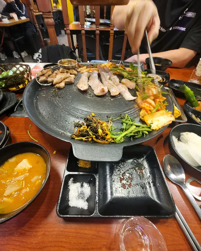 구워진 삼겹살을 젓가락으로 집는 모습