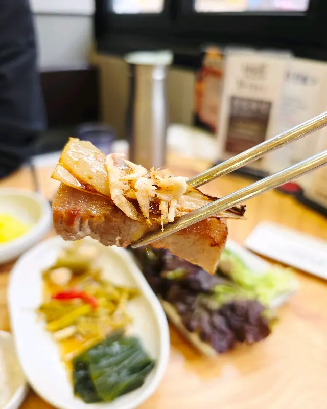 잘 익은 삼겹살을 젓가락으로 집는 모습
