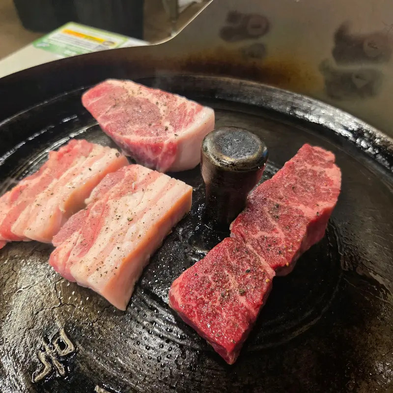 솥뚜껑 위에 구워진 삼겹살과 목살