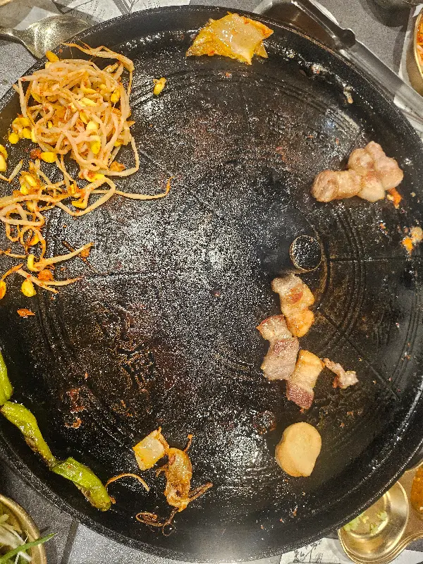 솥뚜껑 위에 구워진 김치와 콩나물