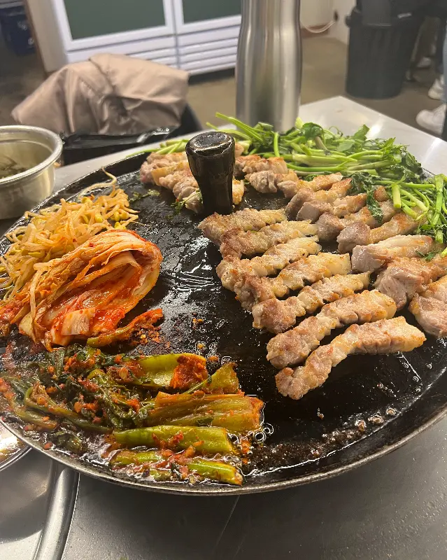 솥뚜껑에 구워진 삼겹살과 곁들임