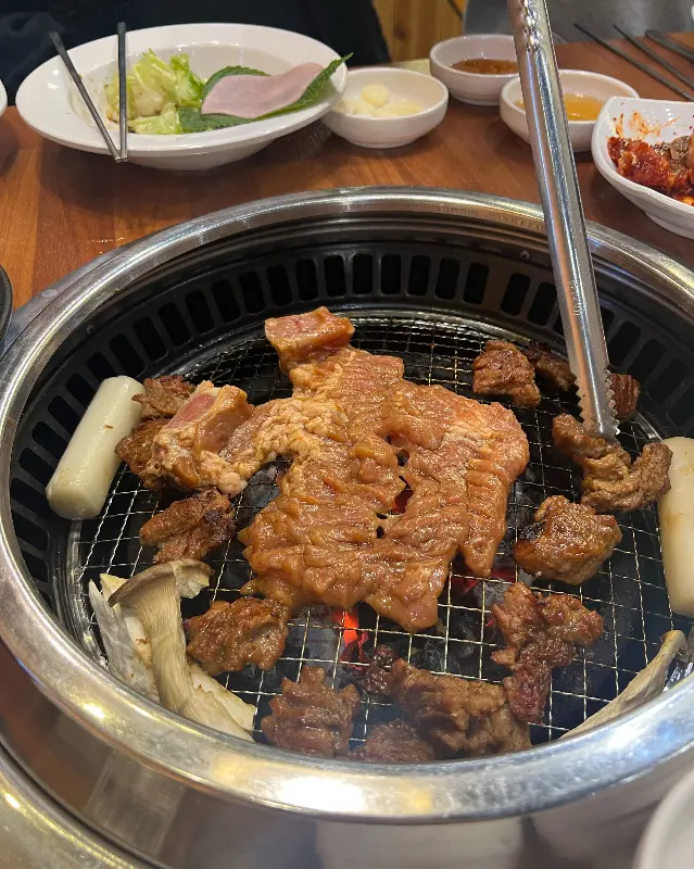 불판 위에서 맛있게 익어가는 돼지갈비와 떡, 버섯