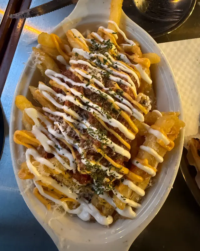 체다 치즈와 소스가 듬뿍 뿌려진 감자튀김