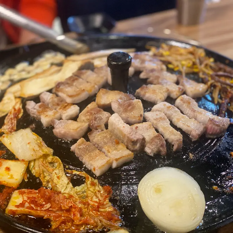 잘 익은 삼겹살과 김치가 솥뚜껑 위에서 조화를 이루는 모습