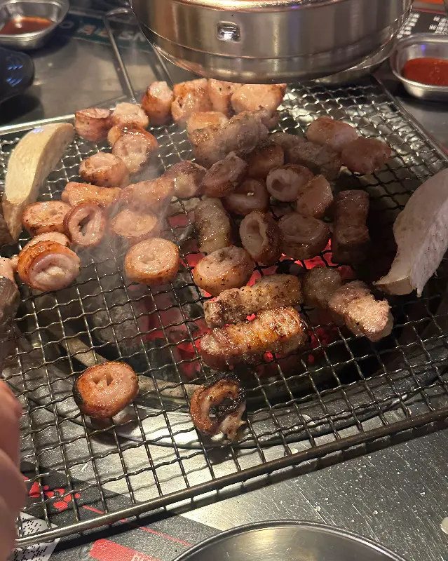 숯불 위에서 노릇하게 익어가는 막창과 버섯