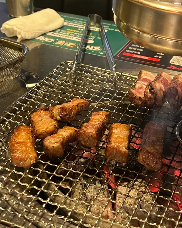 잘 구워진 삼겹살이 숯불 위에 놓여 있는 모습