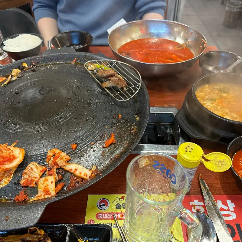 솥뚜껑 옆에 놓인 김치찌개와 밥