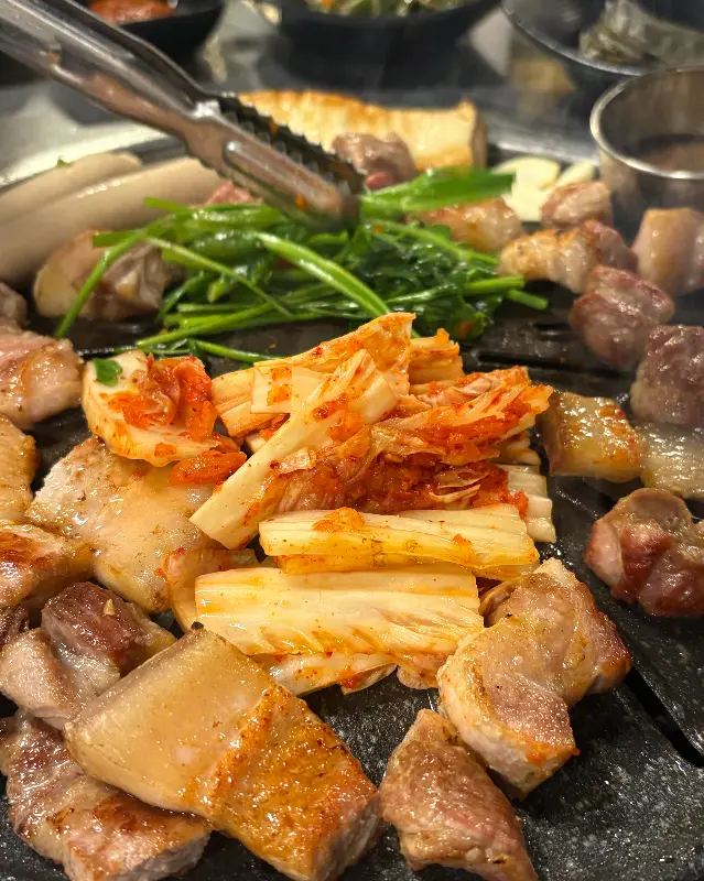 불판 위에서 구워지는 흑돼지 오겹살과 김치
