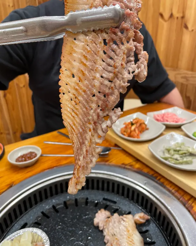 잘 구워진 삼겹살을 들어 올리는 모습