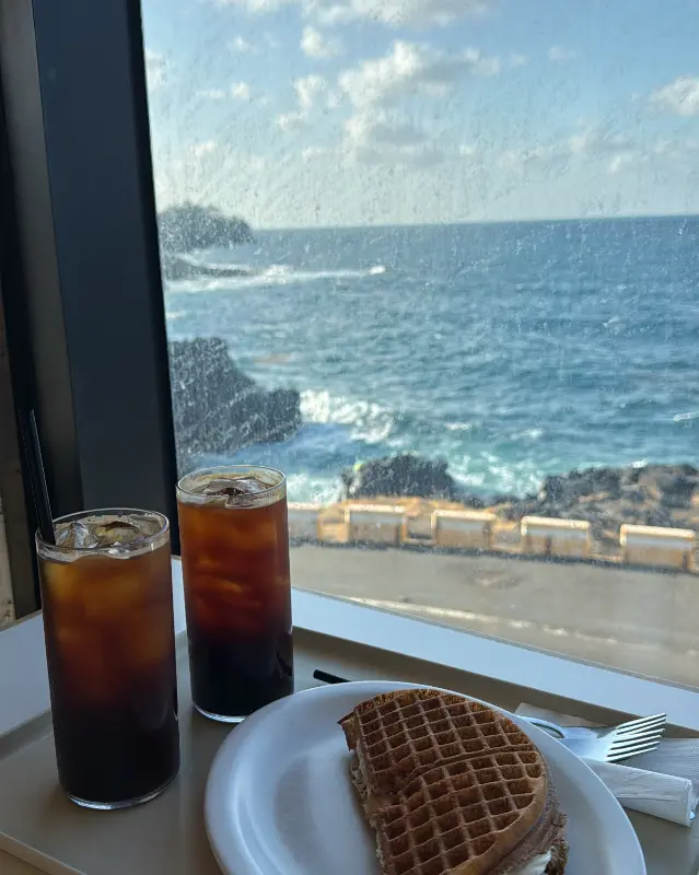 탁 트인 바다를 배경으로 놓인 음료와 디저트