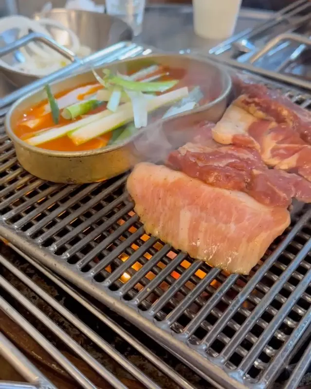 숯불 위에서 맛있게 익어가는 고기와 김치찌개