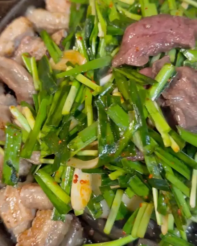 불판 위에 곱창과 부추가 가득 담겨 있는 모습