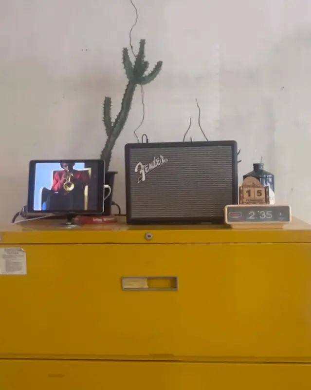 노란색 캐비닛 위에 앰프와 태블릿, 선인장이 놓여 있는 모습. 독특하면서도 감각적인 분위기를 자아낸다.