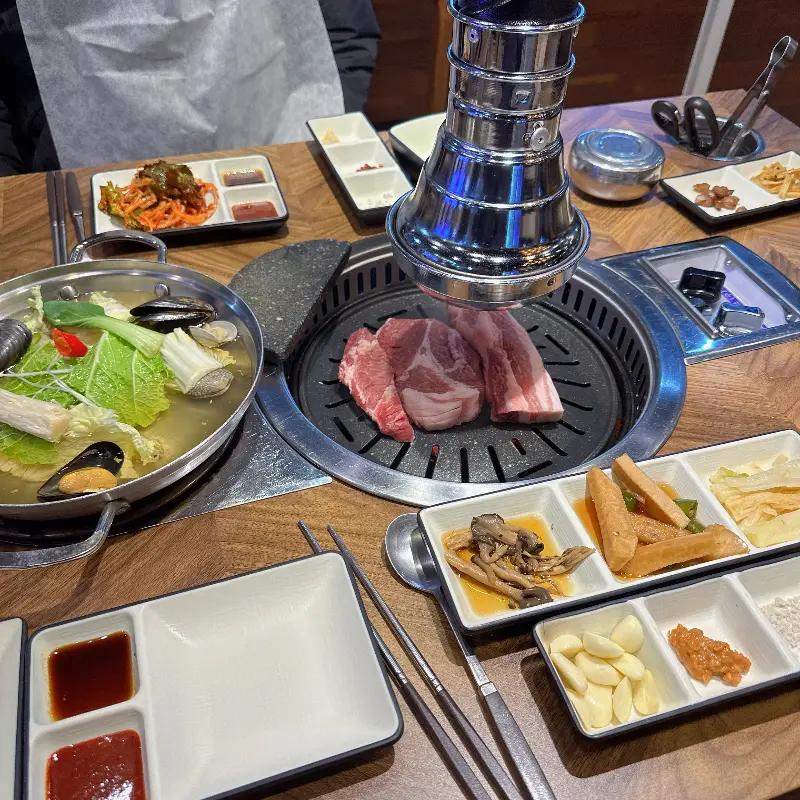 숯불 위에 삼겹살과 조개탕이 함께 놓여진 모습