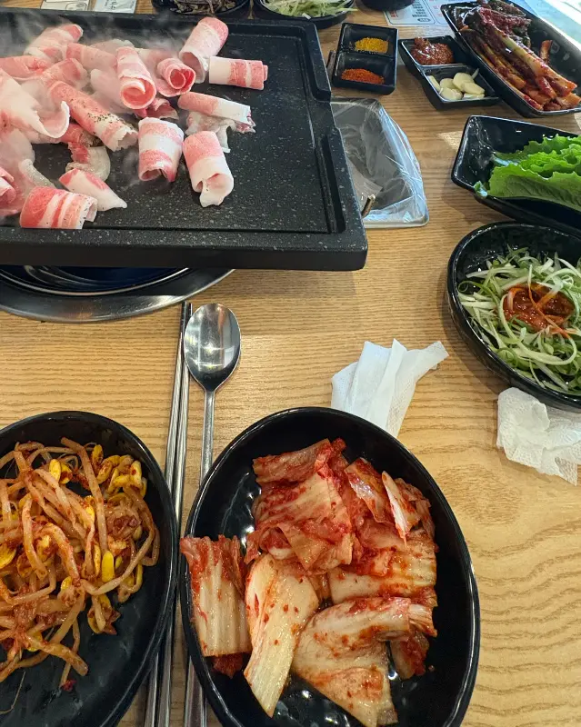 불판 위에서 익어가는 대패삼겹살과 김치